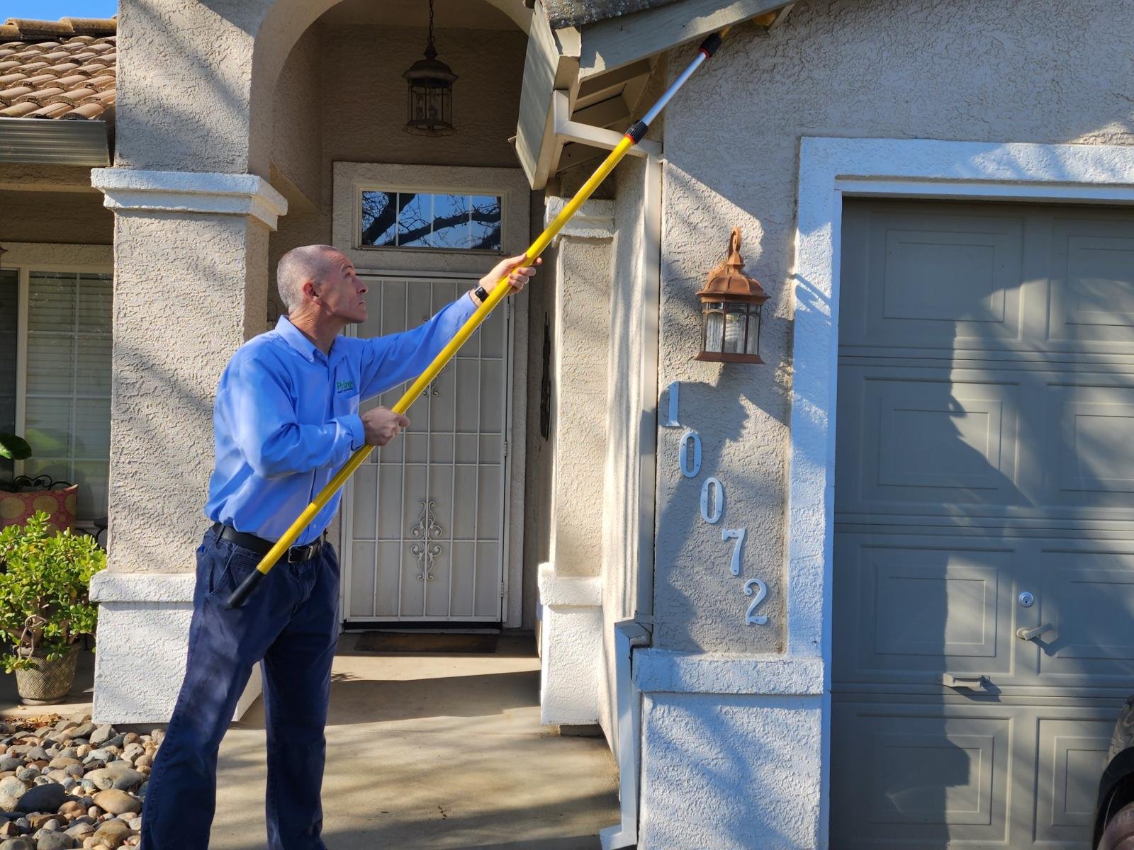 Pest control technician applying treatment on roof and exterior wall