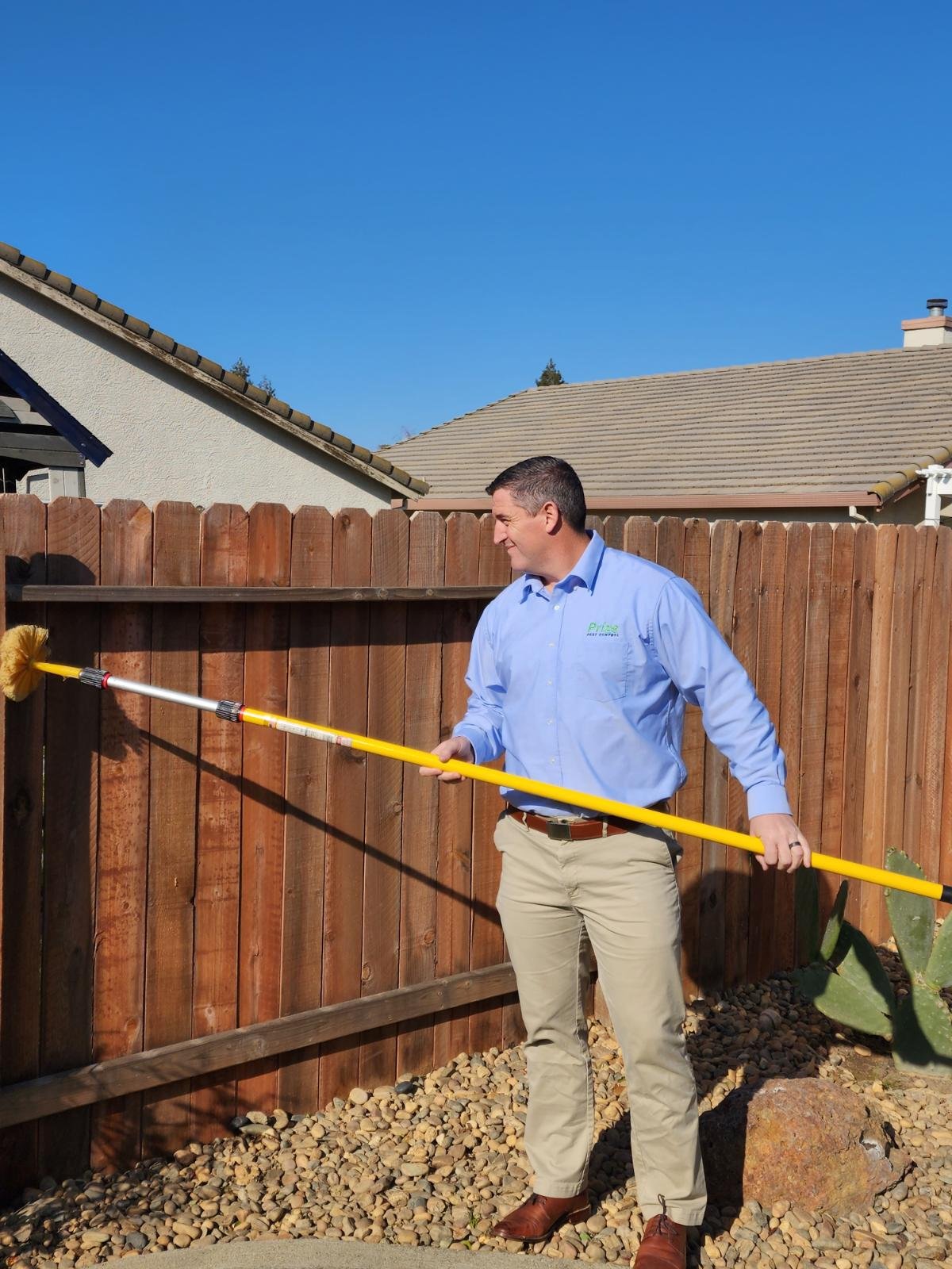Pest control technician applying treatment around home exterior